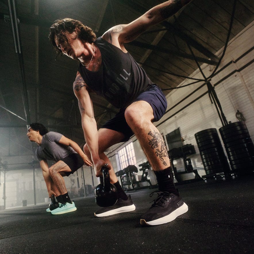 Man using a kettle bell while wearing the jet black classic white drive 2