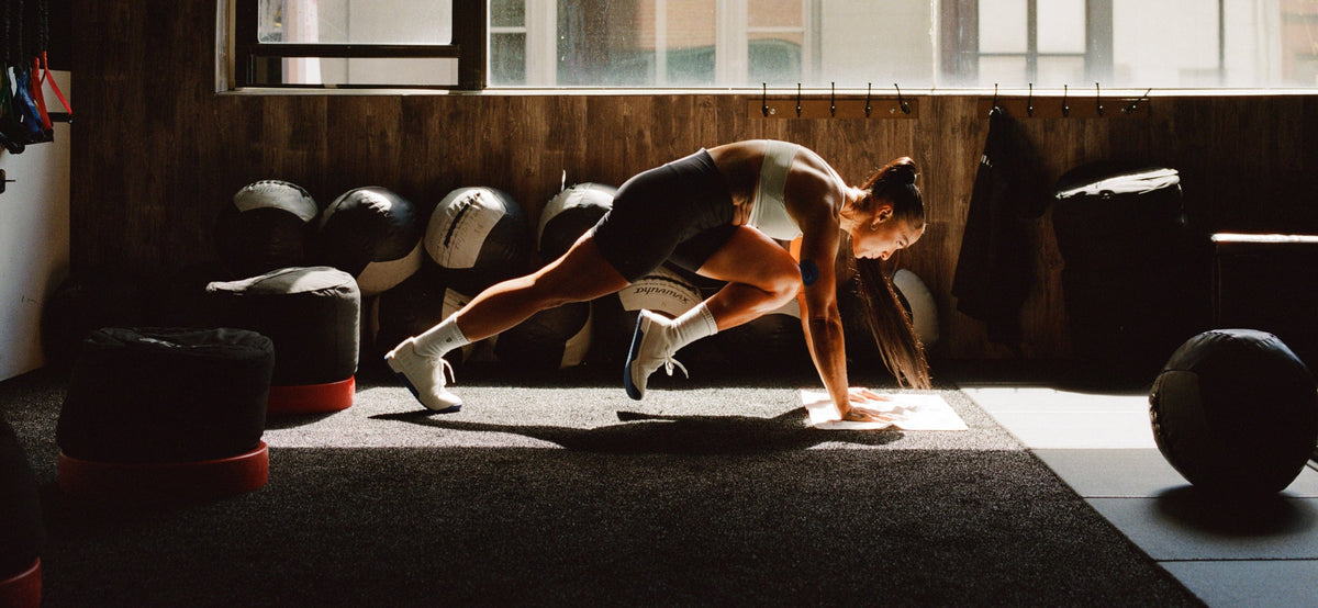 Person doing push-ups in a gym with exercise balls and weights in the background