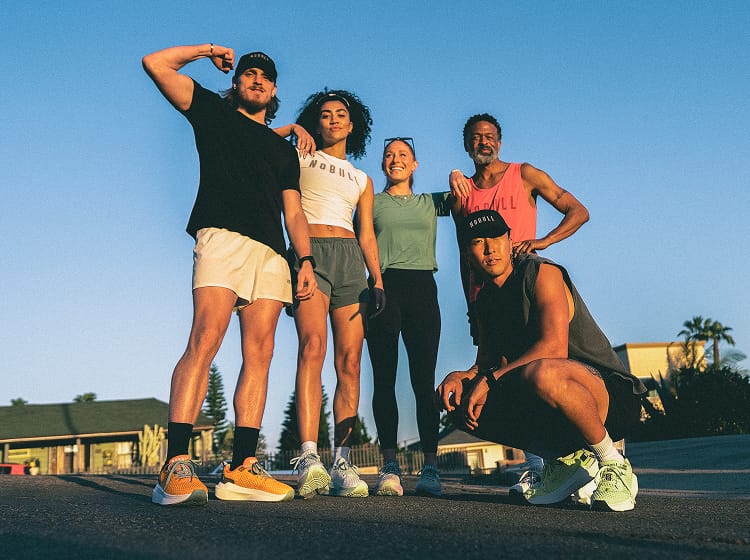 Group of five people posing outdoors on a sunny day