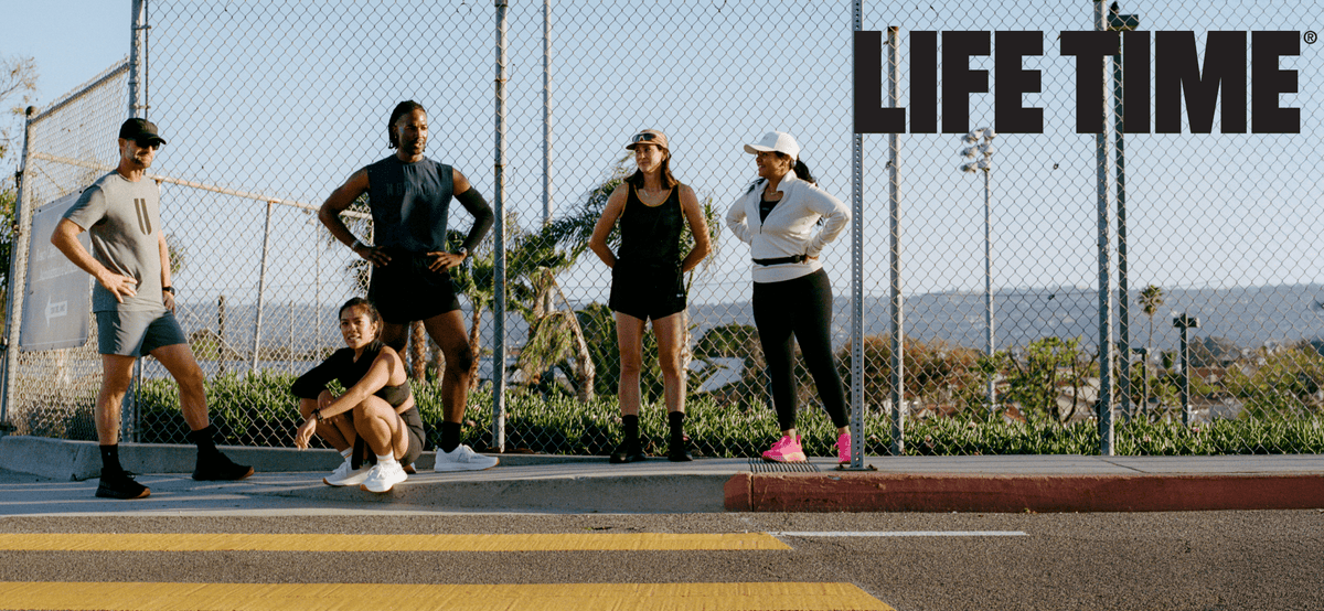 Group of people exercising outdoors with 'LIFE TIME' branding in the background.